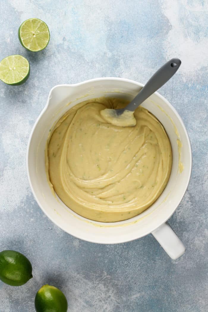 Vanilla cake batter with lime zest mixed in a white bowl.