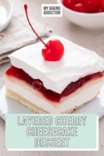 Slice of layered cherry cheesecake dessert topped with a maraschino cherry on a small white plate. Text overlay includes recipe name.