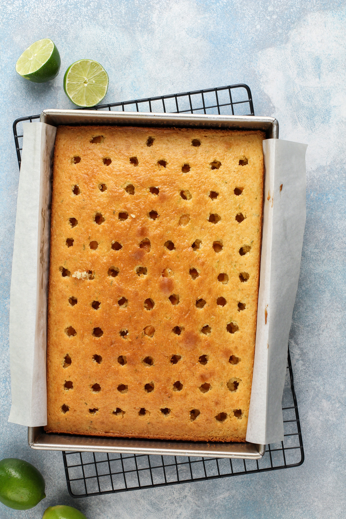 Baked vanilla cake with lime zest in a metal cake pan.