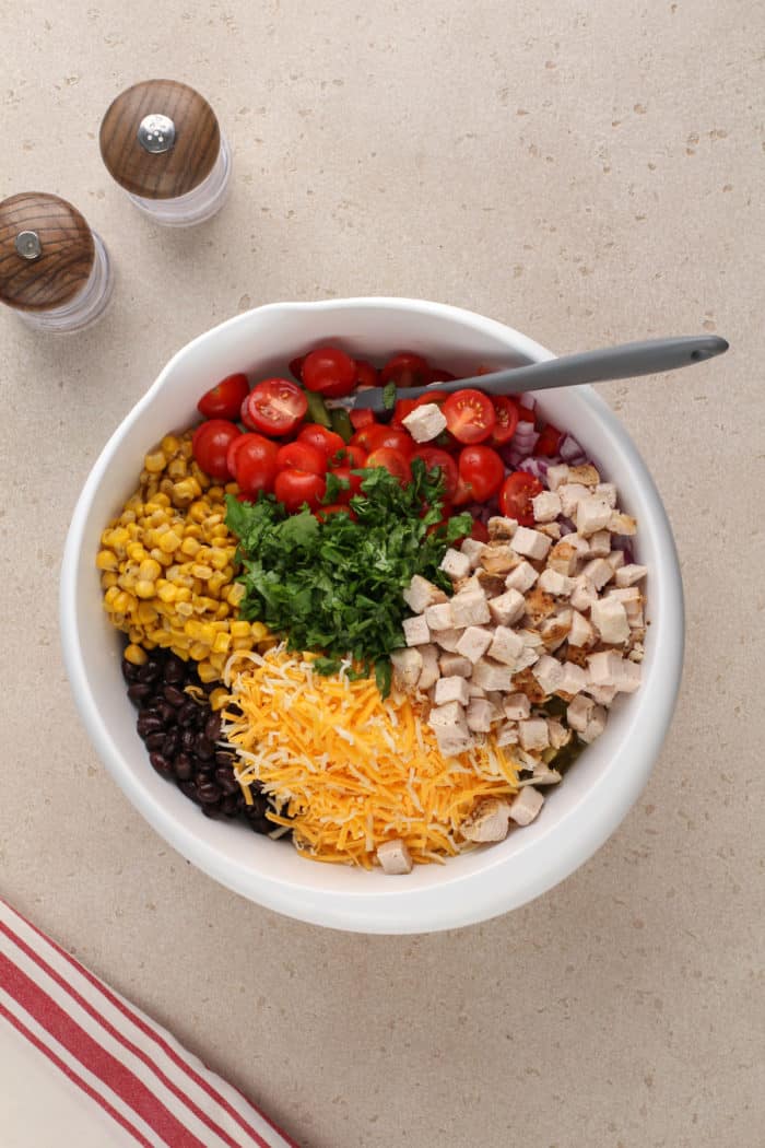 Southwest pasta salad mix-ins added to a white bowl, ready to be stirred together.