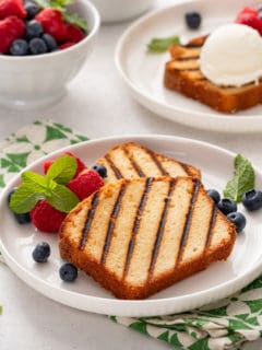 Two white plates, each holding grilled pound cake and fresh berries.