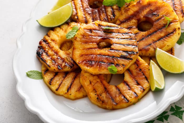 Grilled pineapple slices arranged on a white platter.