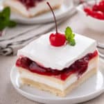 Plated slice of layered cherry cheesecake dessert.