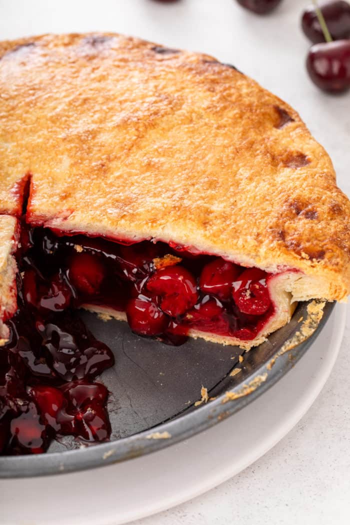 Cherry pie in a metal pie plate, with two slices removed.