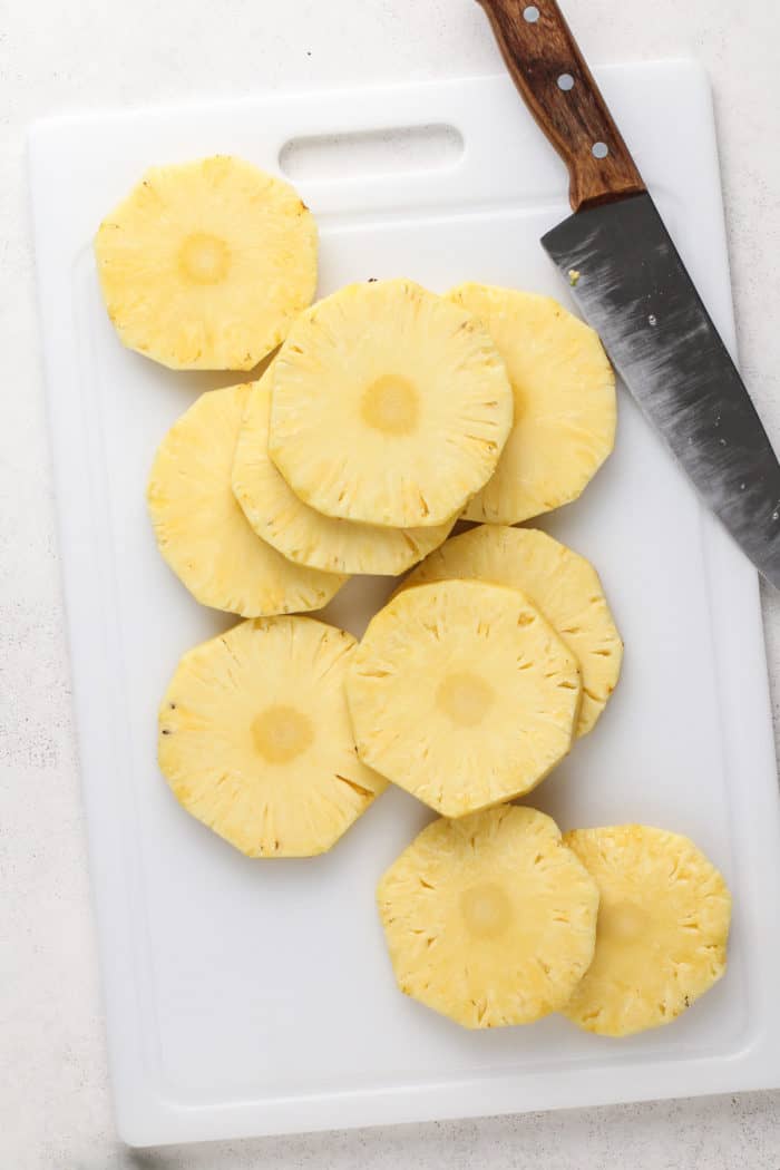 Slices of fresh pineapple on a white cutting board.