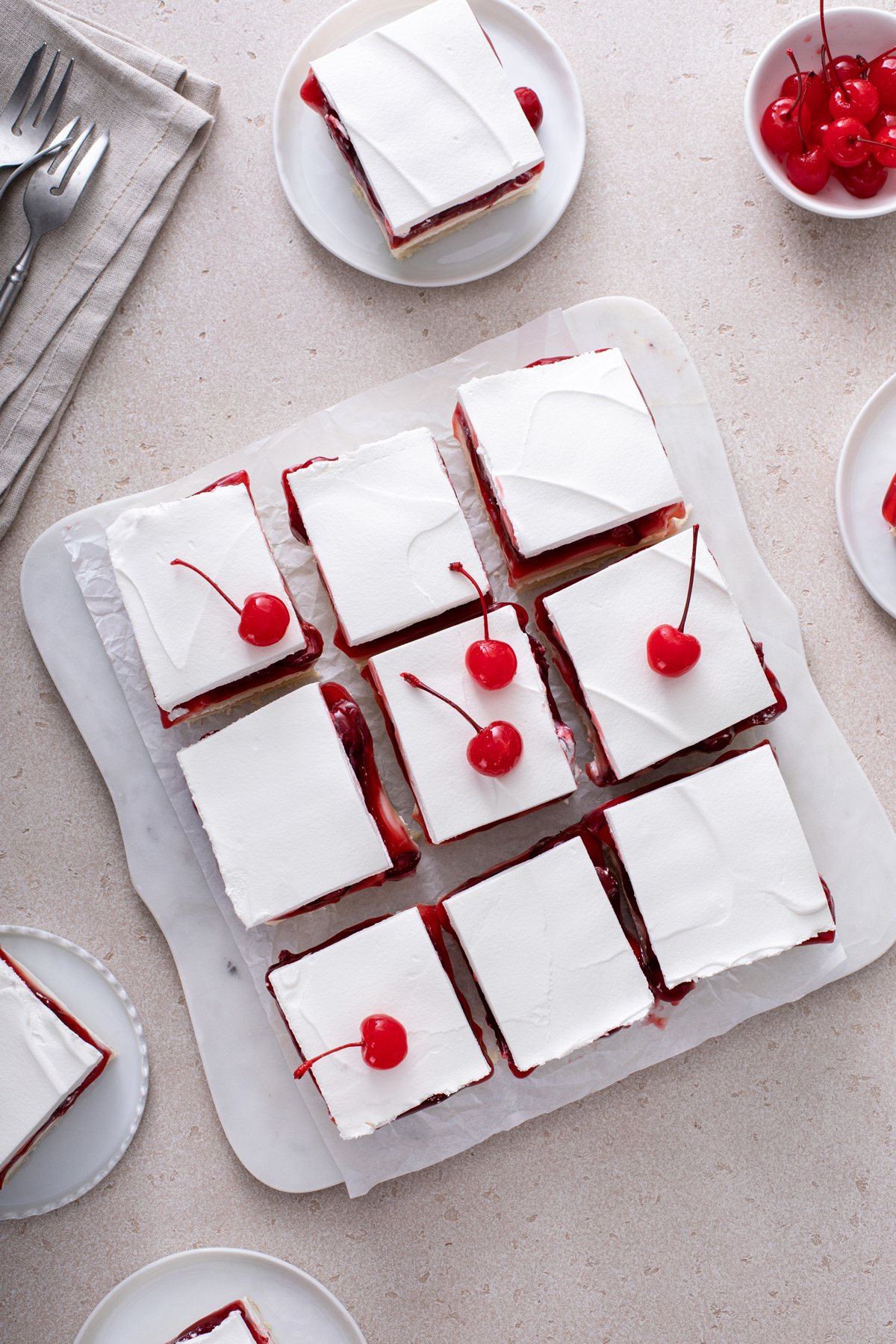 Overhead view of slices of layered cherry cheesecake dessert garnished with maraschino cherries.