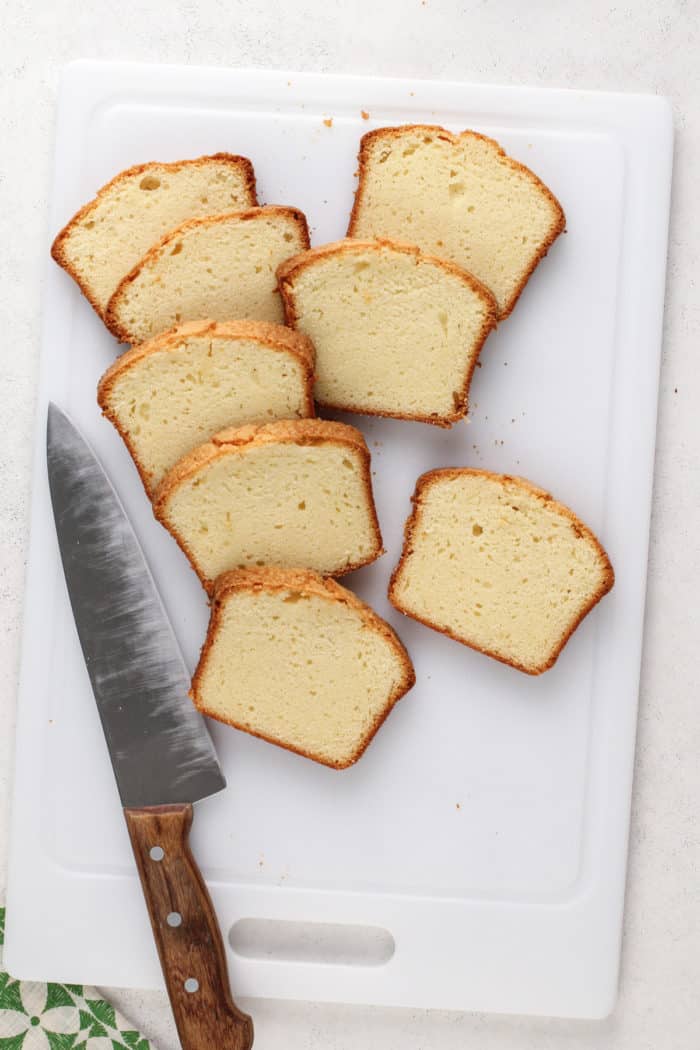 Slices of pound cake next to a knife on a cutting board.