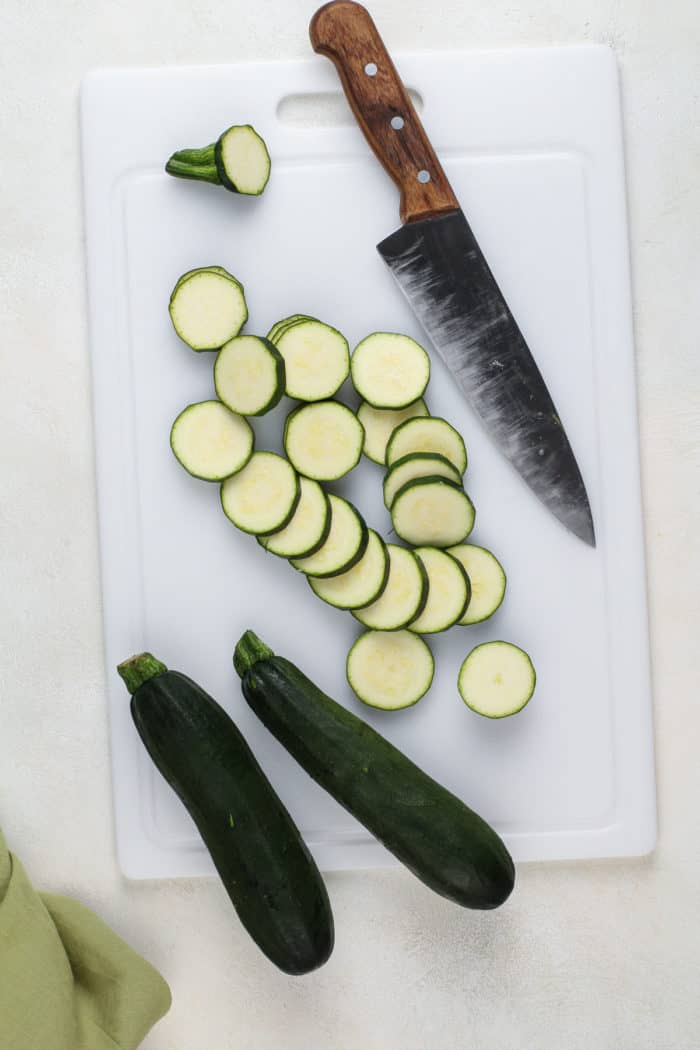 Zucchini cut into equal rounds on a white cutting board.