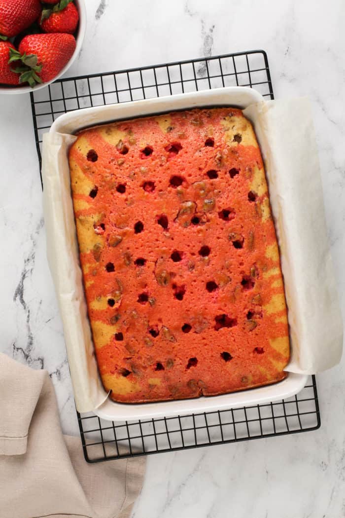 Jello soaked into strawberry poke cake, ready to have the whipped topping added.