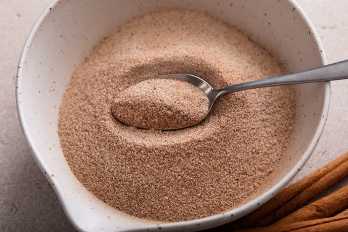 Spoon in a white bowl filled with cinnamon sugar.