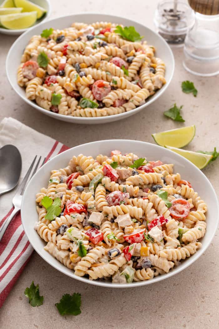 Two white bowls filled with southwest pasta salad on a beige countertop.