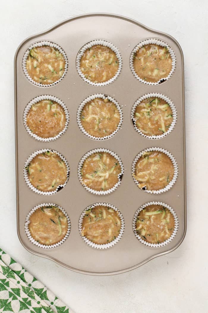 Zucchini muffin batter in a muffin tin, ready to go in the oven.