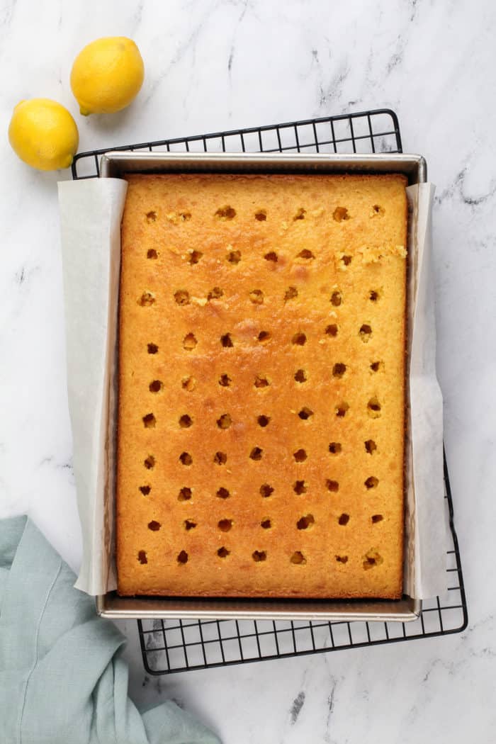 Baked lemon cake with holes poked in it, ready to be assembled as a poke cake.