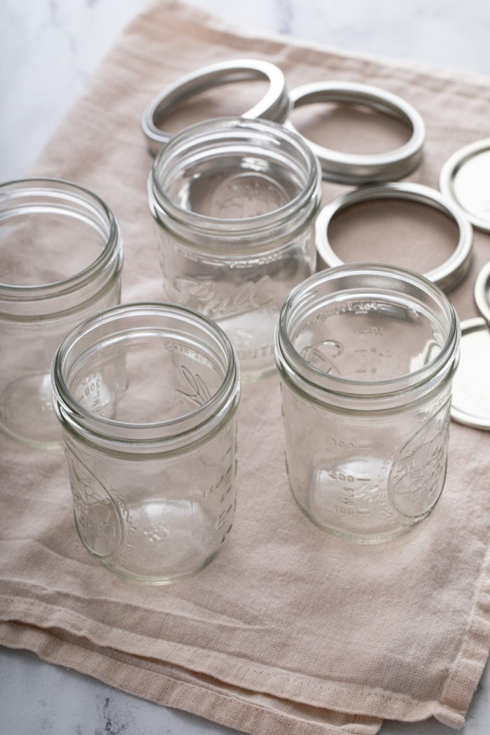 Glass pint jars and lids on a kitchen towel.