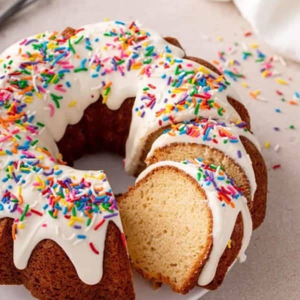 Sliced vanilla bundt cake on a white cake plate.