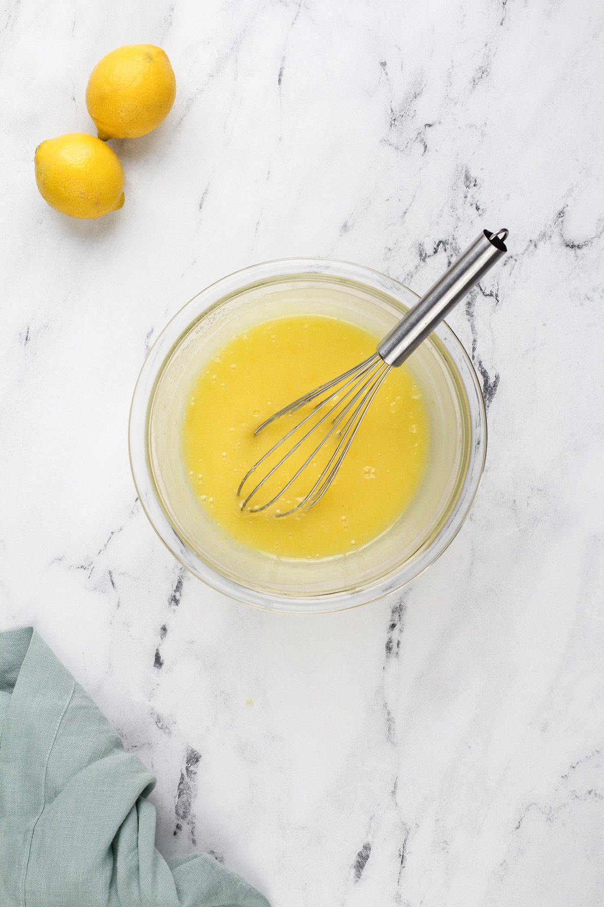 Microwave lemon curd whisked in a glass bowl.