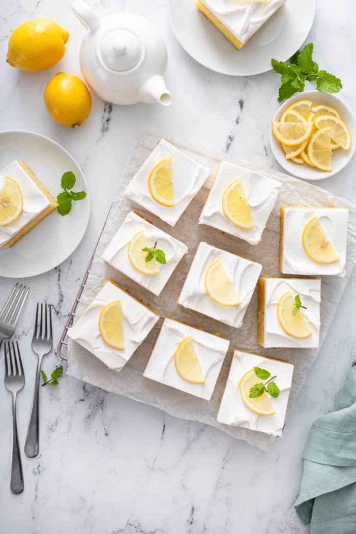 Overhead view of slices of lemon poke cake garnished with fresh lemon slices.