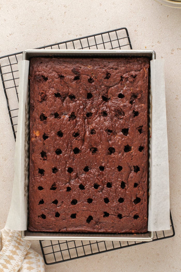 Chocolate butterfinger cake in a cake pan with holes poked across the top.