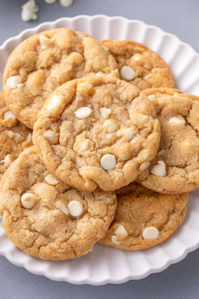 White chocolate macadamia nut cookies piled onto a white platter.