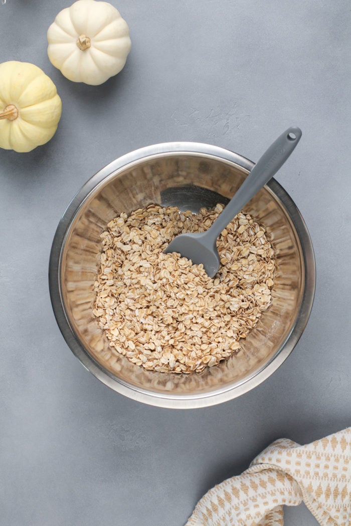 Dry ingredients for pumpkin baked oatmeal in a metal mixing bowl.