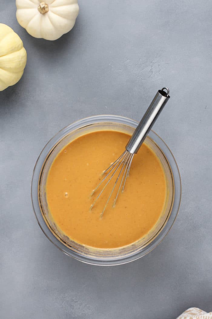 Wet ingredients for pumpkin baked oatmeal in a glass mixing bowl.