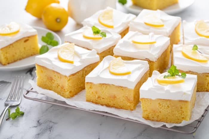 Sliced lemon poke cake on a piece of parchment paper.