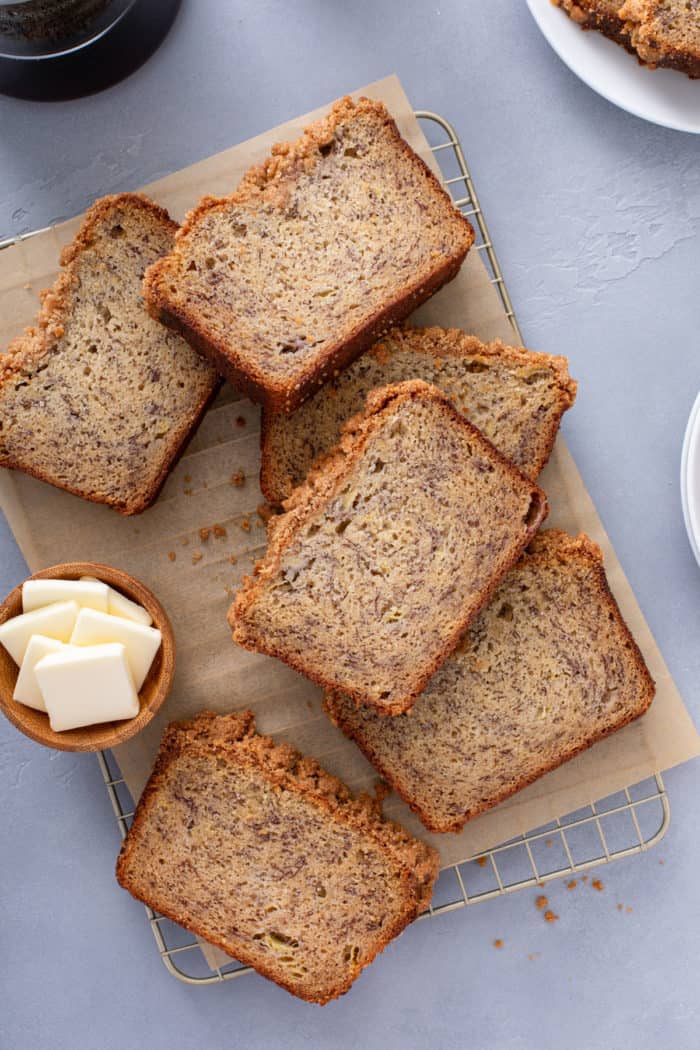 Several slices of brown butter banana bread scattered on a piece of parchment paper.