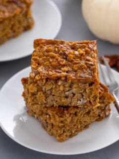 Two slices of pumpkin baked oatmeal stacked on a plate.