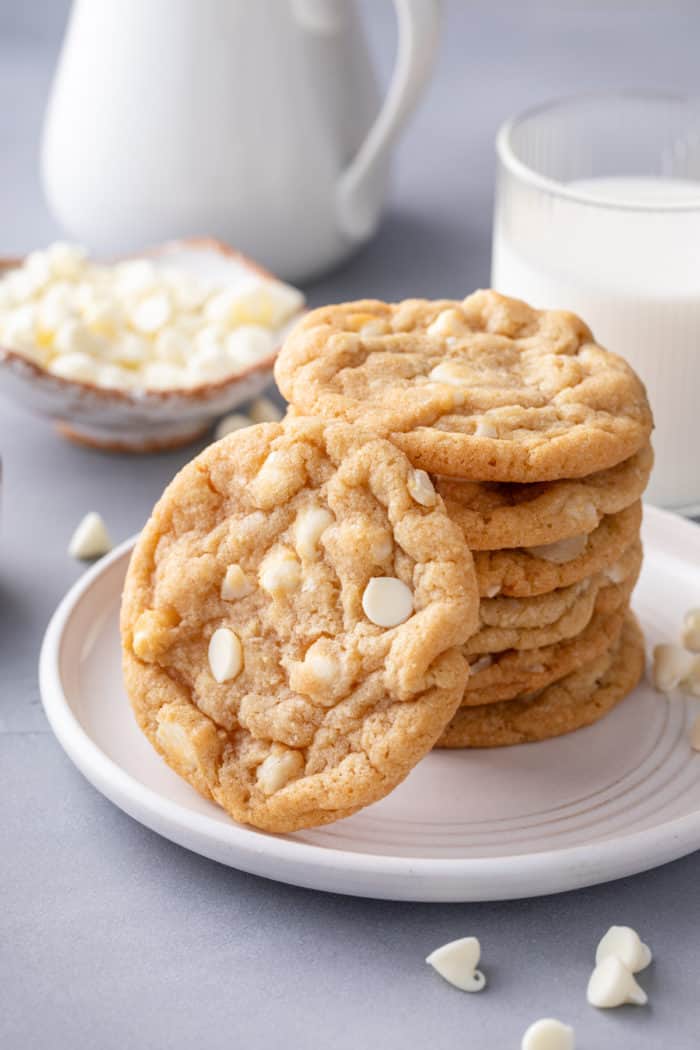 White chocolate macadamia nut cookies stacked on a white plate.