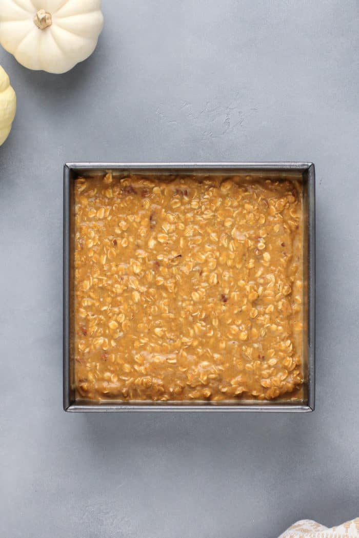 Unbaked pumpkin baked oatmeal in a metal pan, ready to go in the oven.