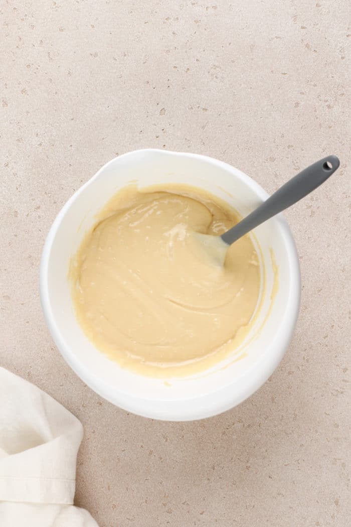 Batter for vanilla bundt cake in a white mixing bowl.