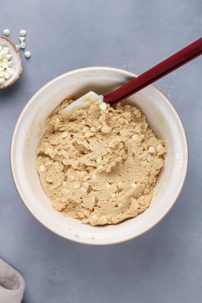 dough for white chocolate macadamia nut cookies in a white mixing bowl.