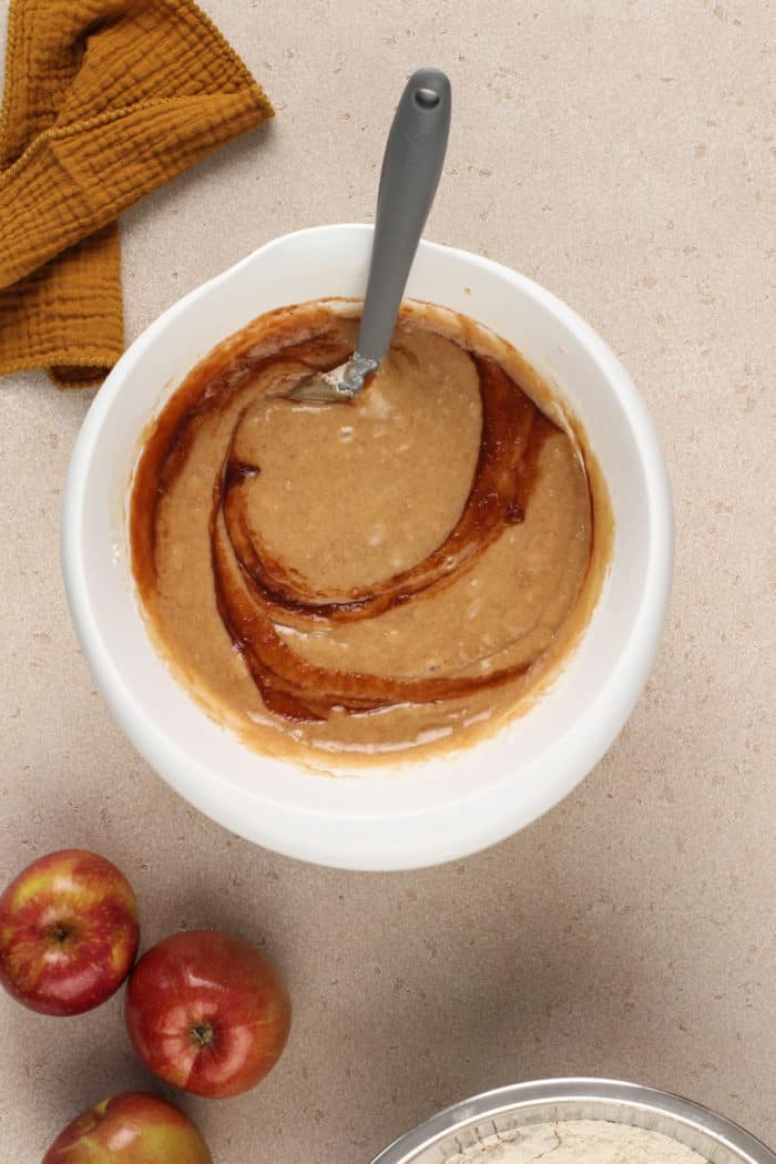 Apple butter being folded into cake batter in a white mixing bowl.
