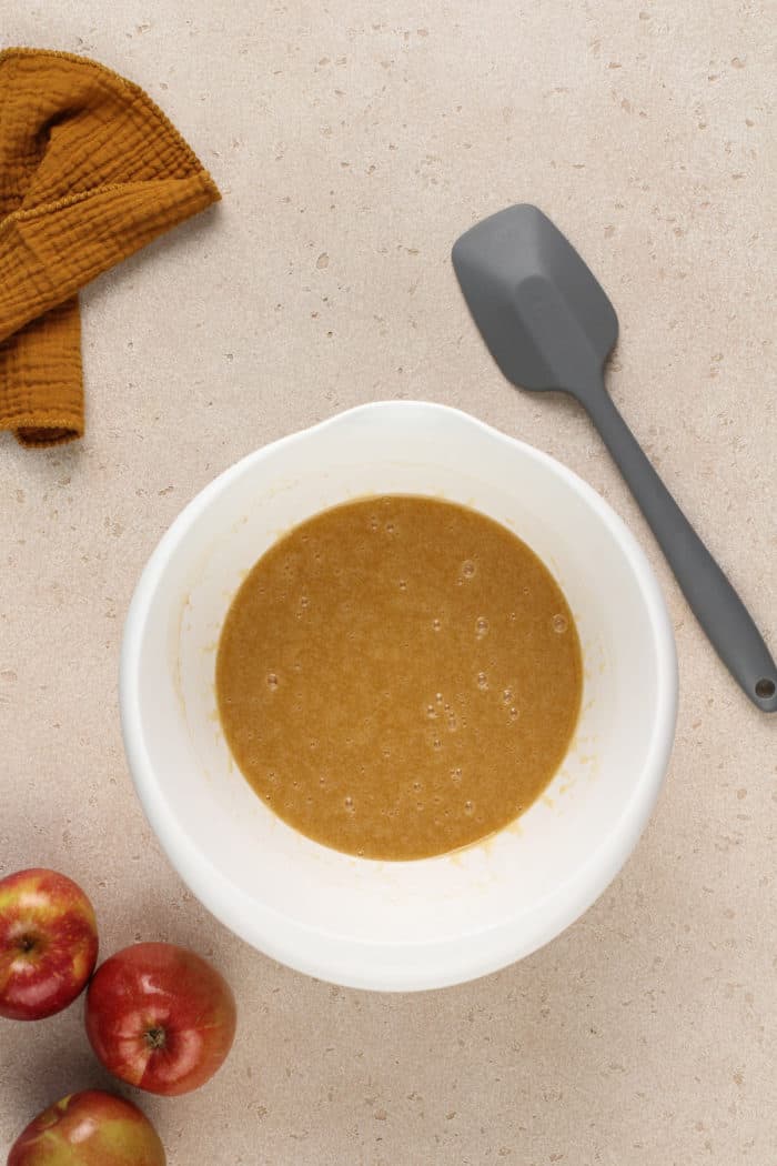 Wet ingredients for apple butter cake in a white mixing bowl.