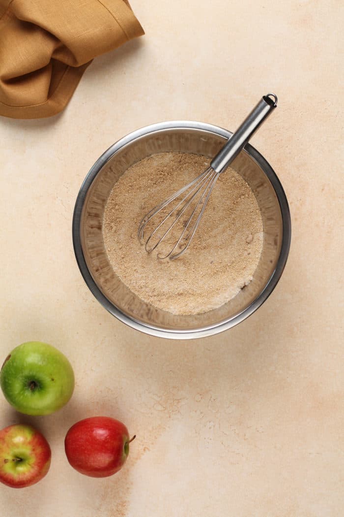 Sugar and spices being whisked in a metal mixing bowl.