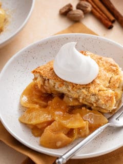 Bowl of apple cobber with whipped cream.