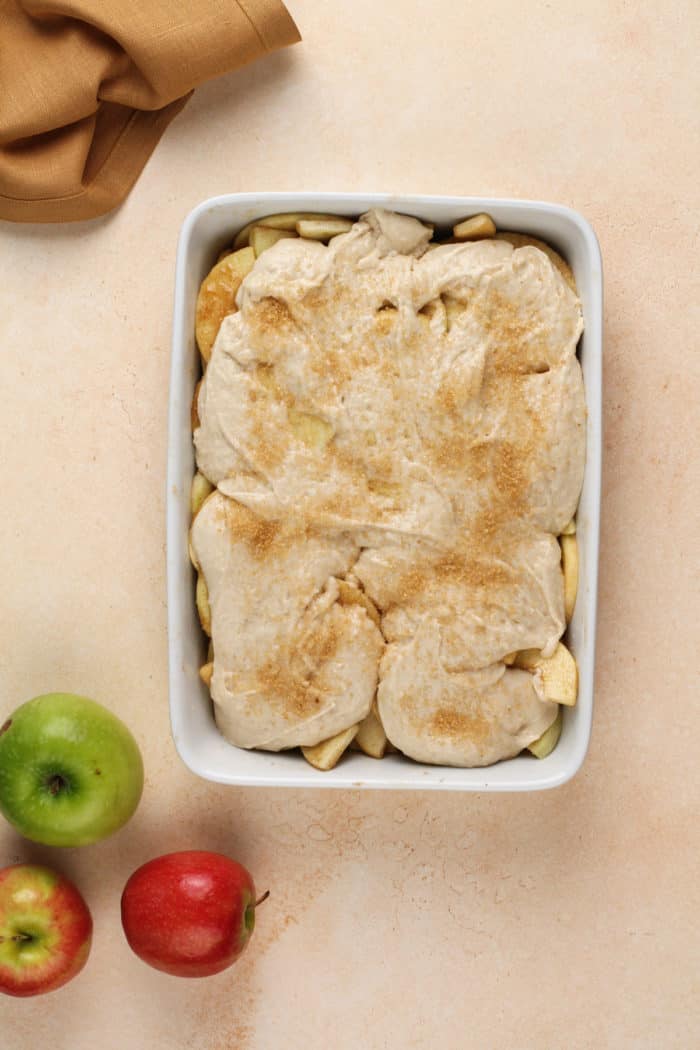 Assembled apple cobbler in a white baking dish, ready to go in the oven.