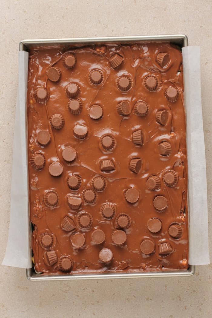 Assembled peanut butter cup rice krispie treats in a parchment-lined pan.