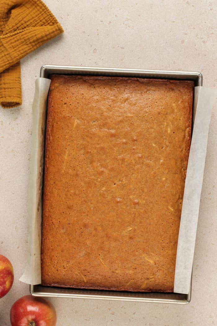 Baked apple butter cake in a parchment-lined cake pan, ready to be frosted.