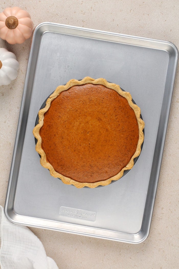 Freshly baked pumpkin cream cheese pie set on a rimmed baking sheet.