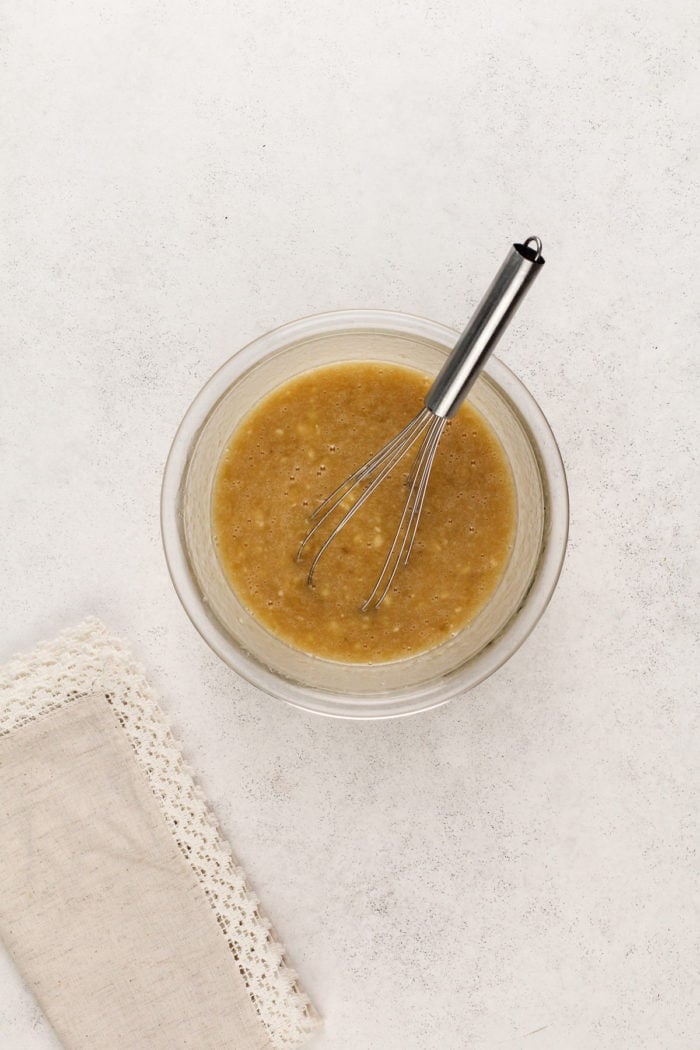 Wet ingredients for banana nut muffins in a glass bowl.