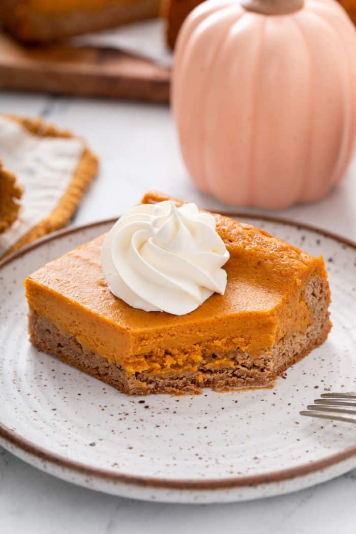 Bite cut from the corner of a plated slice of pumpkin gooey butter cake.