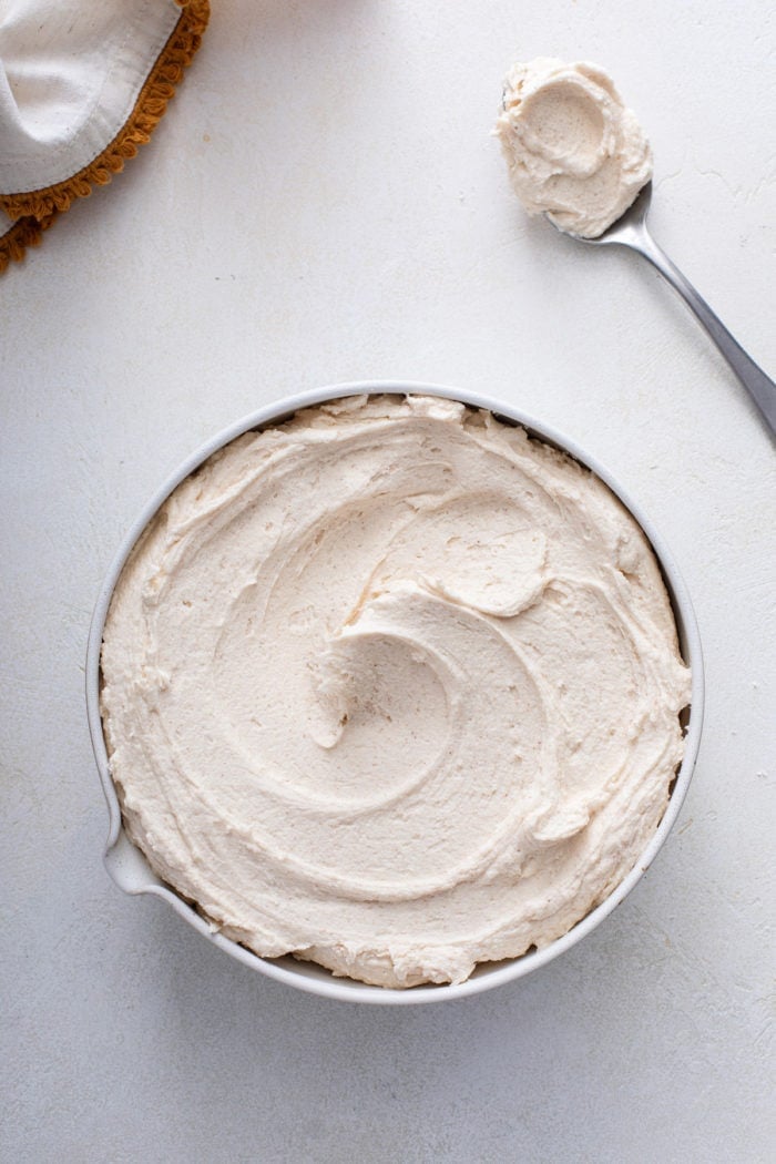 Overhead view of a white bowl filled with brown butter frosting.