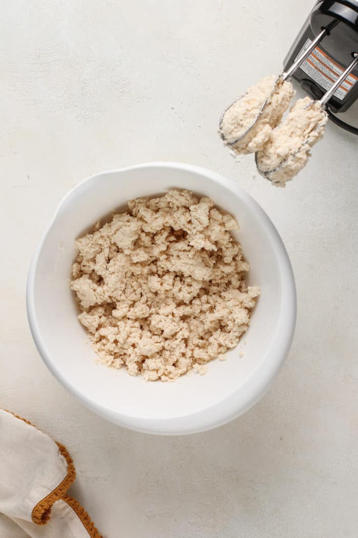 Brown butter and powdered sugar mixed in a white mixing bowl.