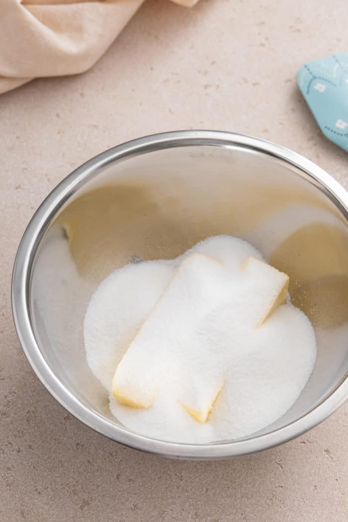 Two sticks of butter and granulated sugar in a metal mixing bowl.