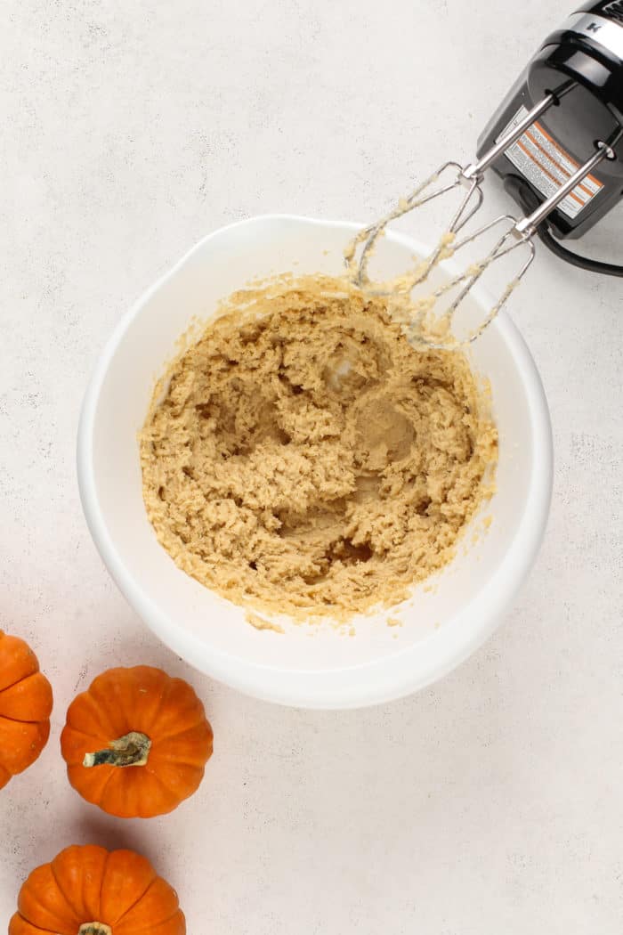 Butter and sugars beaten together in a white mixing bowl.