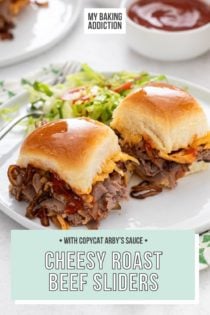 Two cheesy roast beef sliders next to a green salad on a white plate. Text overlay includes recipe name.