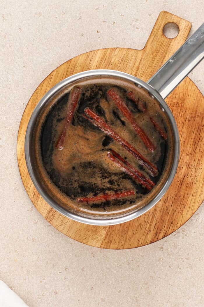 Saucepan filled with brown sugar syrup cooling on a trivet.