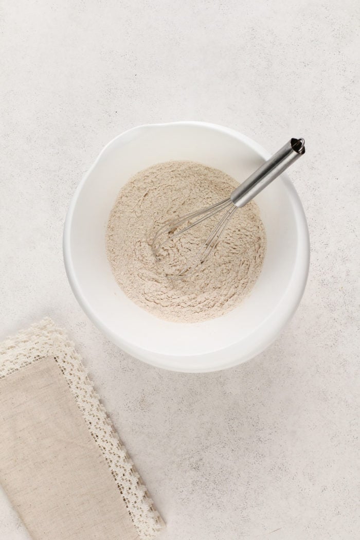 Dry ingredients for banana nut muffins in a white mixing bowl.