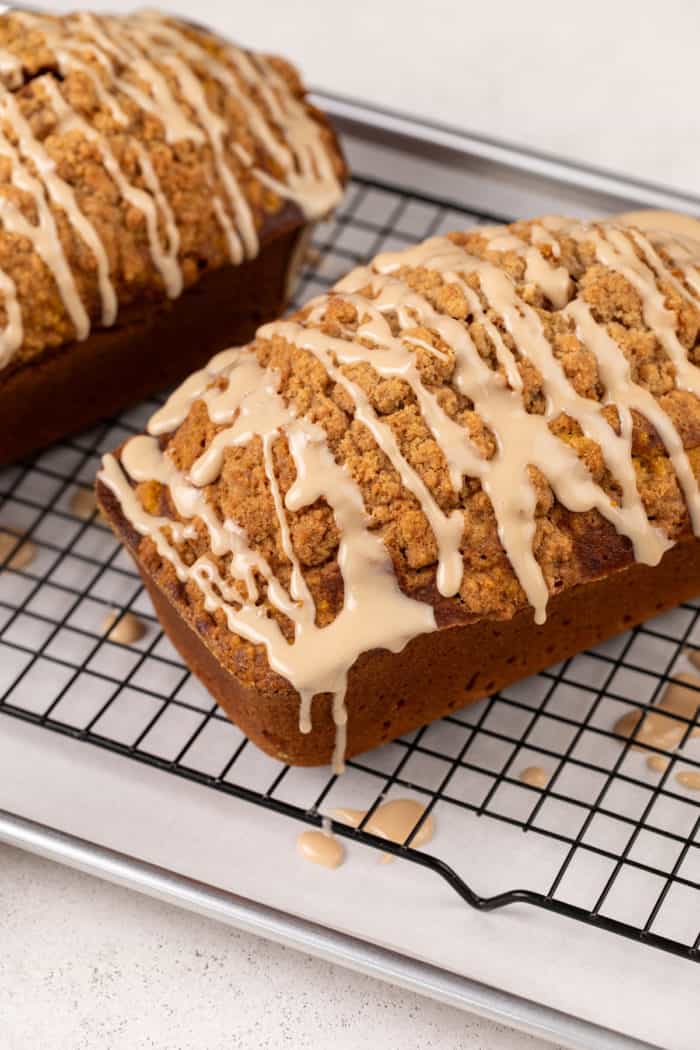 Maple glaze drizzled over streusel-topped pumpkin bread on a wire rack.